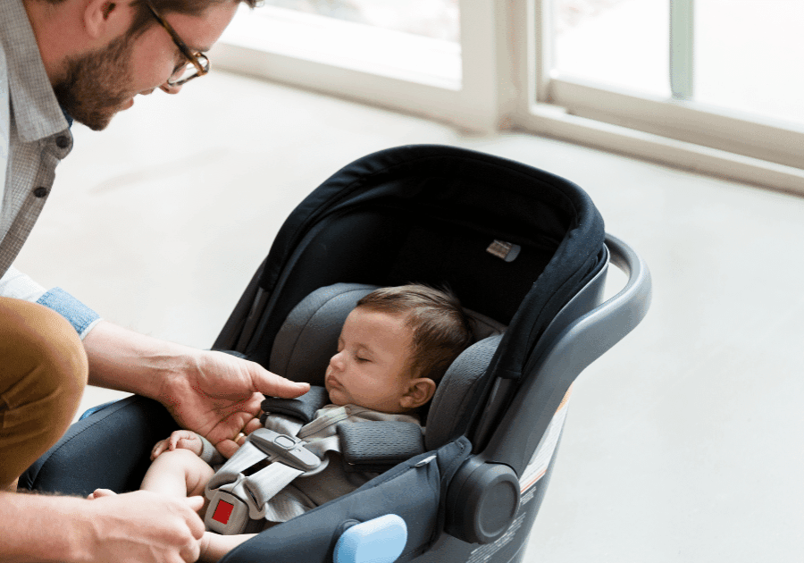 Father secures his newborn in an infant car seat.