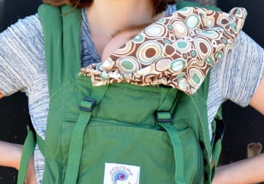 Valuable babywearing tips and the benefits of using carriers or wraps. Mom holding baby in ergo baby carrier